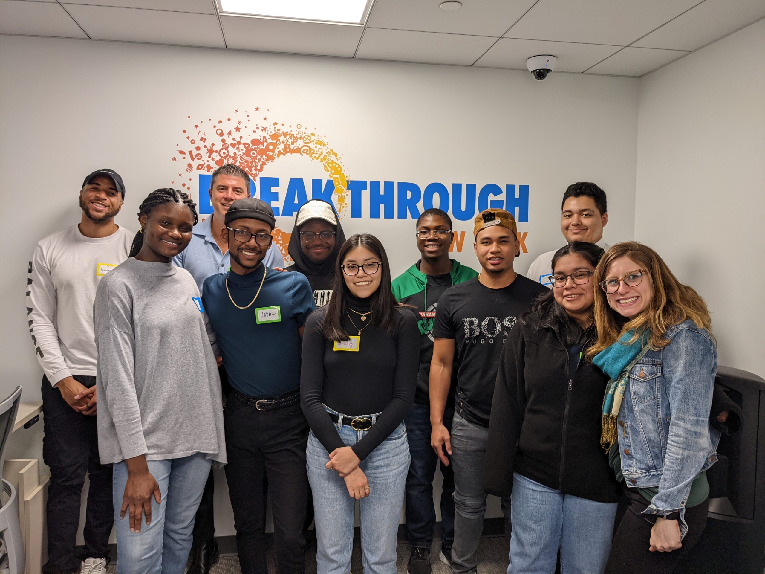 Mentors and mentees stand in front of a Breakthrough New York logo