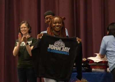 A girl holding up a John Jay College sweatshirt
